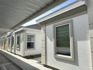 View of side of home featuring a shingled roof, stucco siding, and a patio