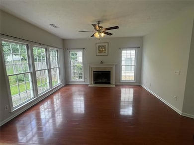 Unfurnished living room featuring plenty of natural light, ceiling fan, a glass covered fireplace, and dark wood-type flooring
