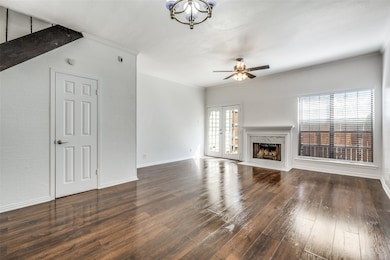Unfurnished living room with dark wood-type flooring, a fireplace, ornamental molding, french doors, and a chandelier
