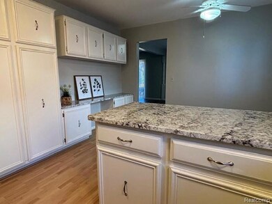 Kitchen with white cabinets, light stone countertops, light wood-style floors, and a ceiling fan
