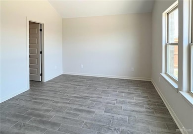 Unfurnished room featuring vaulted ceiling and baseboards