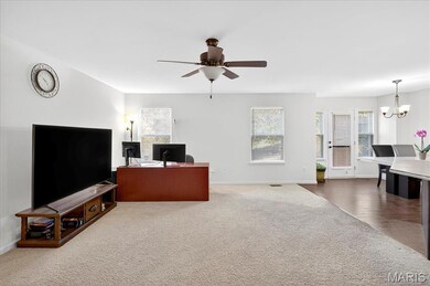 Carpeted home office with a chandelier and ceiling fan