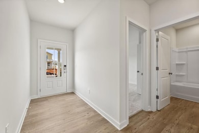 Hallway with light wood-style flooring and baseboa
