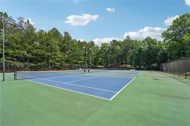 View of tennis court featuring fence and community