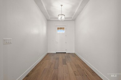 Entryway with wood finished floors, a tray ceiling, and a chandelier