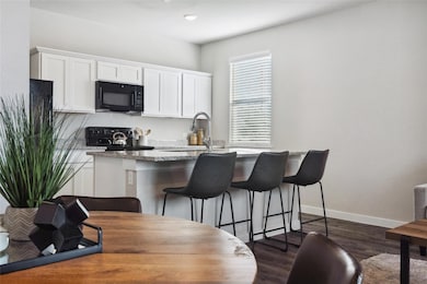 Kitchen with black appliances, a sink, white cabinetry, and a kitchen bar