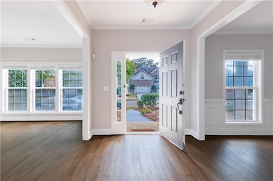 Foyer entrance featuring dark wood-type flooring and crown molding