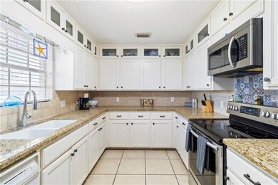Kitchen with white cabinetry, sink, light tile patterned floors, and stainless steel appliances