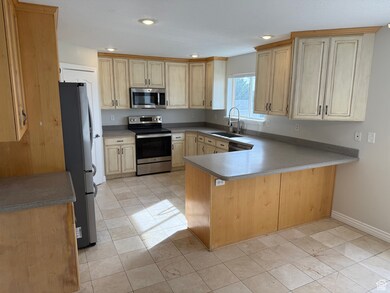Kitchen featuring a peninsula, stainless steel appliances, recessed lighting, light tile patterned floors, and light countertops
