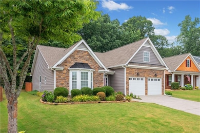 View of front of property featuring stone siding, driveway, a front lawn, and roof with shingles
