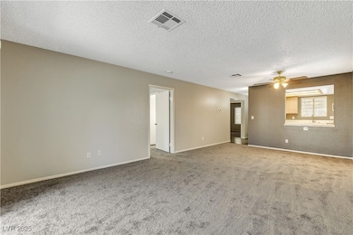 Carpeted empty room featuring a ceiling fan, a tex