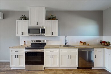 Kitchen with tasteful backsplash, white cabinetry,