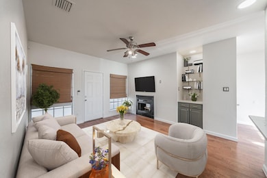 Living room with ceiling fan and light wood-type f