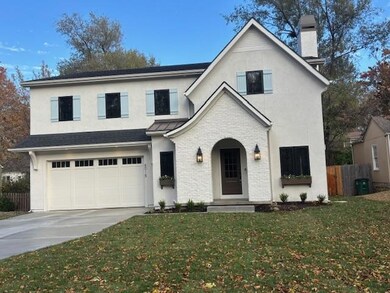 View of front of home featuring concrete driveway, a garage, a chimney, and stucco siding