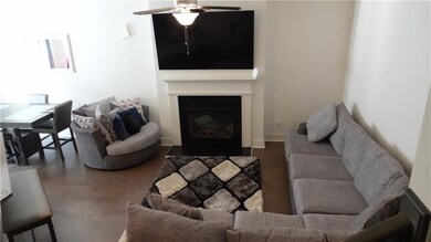Living room featuring ceiling fan, wood finished floors, and a fireplace with flush hearth