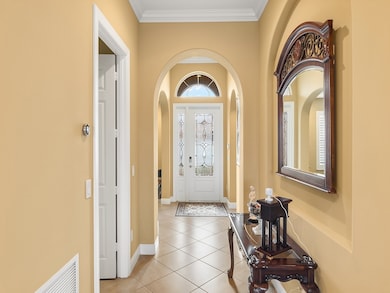Entryway featuring light tile patterned floors, arched walkways, and ornamental molding