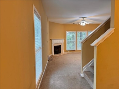 Unfurnished living room with stairs, a fireplace with flush hearth, carpet flooring, and a ceiling fan