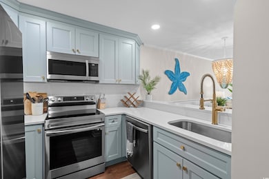 Kitchen featuring appliances with stainless steel finishes, a sink, light countertops, backsplash, and ornamental molding