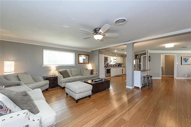 Living room with crown molding, wood finished floors, and ceiling fan