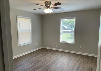 Spare room featuring dark wood-style floors, ceiling fan, and baseboards