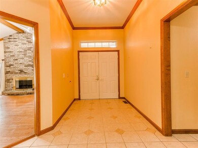 Foyer entrance with brick wall, a brick fireplace, crown molding, and light tile floors