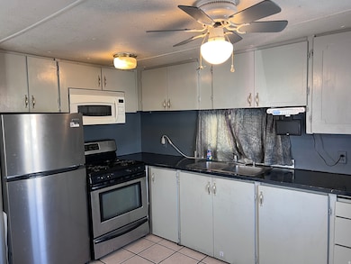Kitchen with stainless steel appliances, light tile patterned floors, dark countertops, gray cabinets, and a textured ceiling