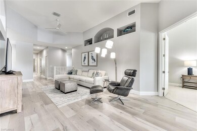 Living room with ceiling fan, a towering ceiling, and light hardwood / wood-style floors