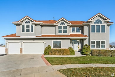 Townhome / multi-family property featuring a front yard, a garage, driveway, stucco siding, and a tiled roof
