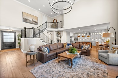 Living room featuring a chandelier, ornamental molding, hardwood / wood-style flooring, recessed lighting, and stairway
