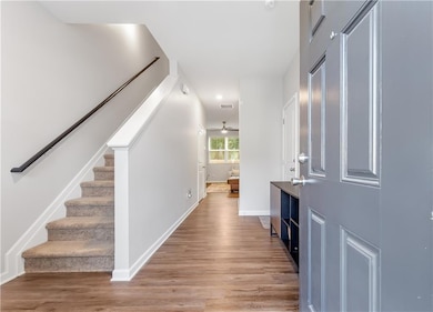 Entrance foyer featuring stairway, light wood-type flooring, baseboards, and a ceiling fan