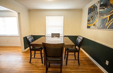 Dining space with ornamental molding, wood finished floors, and a textured ceiling