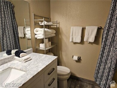 Full bathroom featuring wood finished floors, vanity, a textured wall, and curtained shower