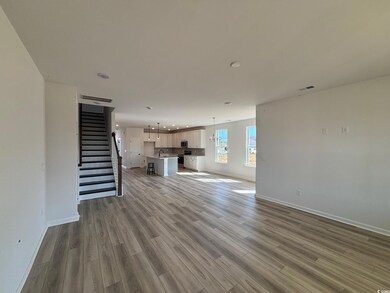 View of the kitchen and family room with LVP, boxed oak stair treads with matching handrail and 6ft windows around the perimeter of the open concept family room.