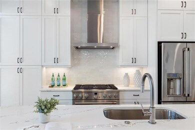 Kitchen featuring appliances with stainless steel finishes, wall chimney exhaust hood, white cabinetry, and backsplash