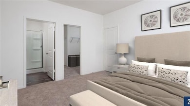 Carpeted bedroom featuring a walk in closet, ensu