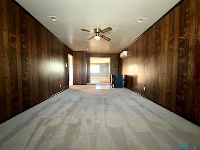 Den featuring light carpet, wood walls, and ceiling fan