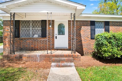 Entrance to property with covered porch and brick 