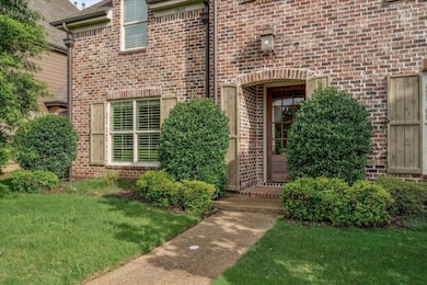 View of exterior entry with brick siding and a lawn