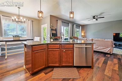 Kitchen featuring pendant lighting, dishwasher, an island with sink, healthy amount of natural light, and a textured ceiling