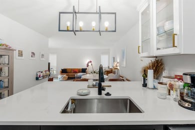 Kitchen with open floor plan, white cabinetry, gl