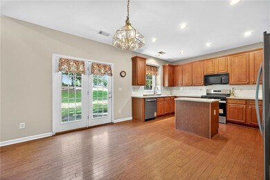 Kitchen with a kitchen island, decorative backsplash, stainless steel appliances, brown cabinetry, and pendant lighting