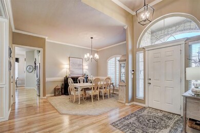 Foyer with crown molding, light wood-style flooring, a notable chandelier, and baseboards