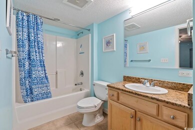 Bathroom featuring a textured ceiling, shower / bathtub combination with curtain, vanity, and tile patterned flooring