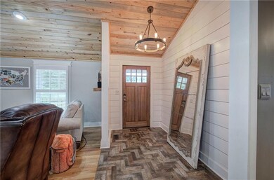Foyer entrance with lofted ceiling, wood ceiling, wood walls, a chandelier, and plenty of natural light