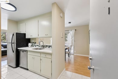 Kitchen featuring appliances with stainless steel finishes, light tile patterned floors, white cabinets, decorative backsplash, and light stone countertops
