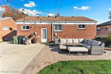 Back of property featuring a patio area, outdoor lounge area, a chimney, brick siding, and roof with shingles