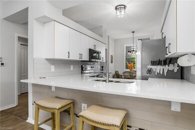 Kitchen with stainless steel appliances, a peninsula, backsplash, and white cabinets