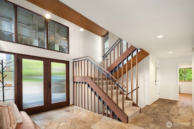 Lofty double-door entry with leaded glass windows & flagstone flooring.