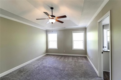 Spare room featuring a raised ceiling, ceiling fan, carpet floors, and crown molding