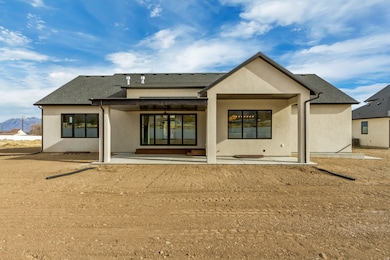 Back of house with a patio area, stucco siding, a shingled roof, and a mountain view